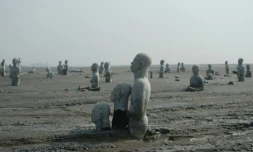 Vue en date du 28 mars 2016 de sculptures de personnes à moitié enterrées dans le volcan de boue qui a surgi de terre le 29 mai 2006 à Sidoarjo