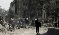 Des gens fuient avec leurs affaires leur maison dans la ville de Hammouriyé, dans la Ghouta orientale, près de Damas, le 15 mars 2018, alors que les forces du régime poursuivent leur offensive contre les secteurs rebelles dans ce secteur