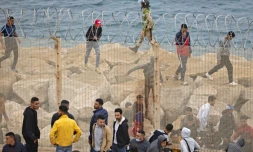 Des migrants marocains passent Ă travers une barriĂšre de la ville de Fneideq vers l'enclave espagnole de Ceuta le 18 mai 2021