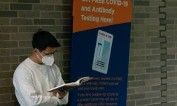 Un homme lit un livre dans la file d'attente d'un centre de dépistage du Covid-10 à l'hôpital Bellevue de New York, le 19 août 2020