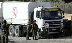 Des soldats russes se tiennent le 8 mars 2018 à un check-point à la péripéhérie de Damas près d'un camion d'aide humanitaire destinée aux habitants d'une enclave rebelle
