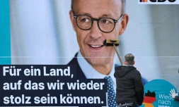 Un homme colle une affiche de Friedrich Merz, leader des conservateurs allemands et favori à la chancellerie, le 13 janvier 2025 à Berlin, en vue des élections législatives anticipées du 23 février