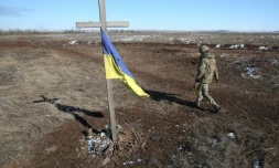 Un soldat ukrainien passe à cÎté d'un mémorial de fortune à Svetlodarsk, prÚs de Donetsk, en Ukraine, le 12 mars 2022