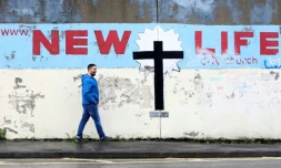 Un homme passe devant le mur qui sépare les deux communautés à l'ouest de Belfast, devenu une attraction touristique, le 16 mars 2023