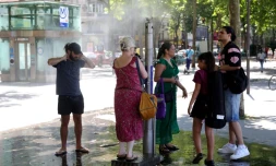 Des passants se rafraîchissent grâce à une fontaine brumisante à Paris, le 21 juin 2025