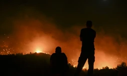 Des personnes observent un incendie près du village de Malona sur l'île grecque de Rhodes le 23 juillet.