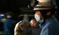 Capture d'écran d'une vidéo fournie par la préfecture de police de Kunamoto le 15 avril 2016 montrant un sauveteur sortant des décombres un bébé de huit mois, après un séisme qui a fait neuf morts au Japon
