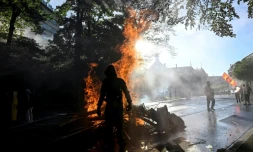 Manifestant devant une poubelle en feu lors d'une manifestation anti-G7 à Genève, le 14 juin 2026
