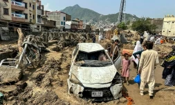 Des habitants de Mingora sont réunis autour d'un véhicule endommagé et de débris après l'effondrement de la route suite aux crues subites dans la province montagneuse de Khyber Pakhtunkhwa au Pakistan le 16 août 2025