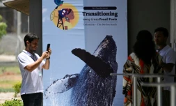 Des personnes prennent une photo devant une affiche de la conférence pour une sortie des énergies fossiles, à Santa Marta, en Colombie, le 26 avril 2026