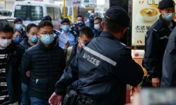 Le rédacteur en chef de Stand News, Patrick Lam, est conduit menotté par la police dans les locaux du site d'information pendant une perquisition, le 29 décembre 2021 à Hong Kong
