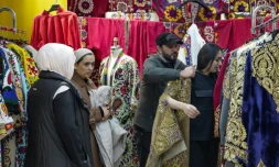 Le styliste Khourched Sattorov présente des vêtements traditionnels à des clientes dans son atelier à Douchanbé, le 2 décembre 2024 au Tadjikistan