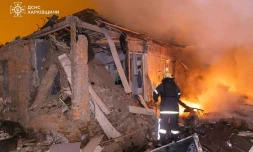 Photo diffusée le 26 février 2026 par le Service ukrainien des situations d'urgence montrant un pompier éteignant un incendie dans une maison endommagée aprÚs une attaque russe à Kharkiv
