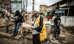 Des kenyans lisent le journal, dans l'attente des résultats définitifs de l'élection présidentielle, dans le bidonville de Kawangare à Nairobi, le 10 août 2017
