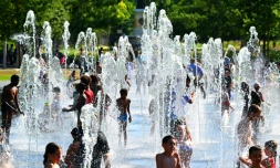 Des enfants se rafraîchissent dans les jets d'eau d'une fontaine à Reims, dans le nord-est de la France, le 1er juillet 2025