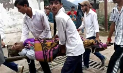 Des hommes transportent un blessé dans une civière à l'hôpital de Kishtwar en Inde le 14 août 2025 après des inondations au Cachemire 