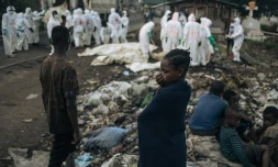 De jeunes habitants regardent des membres de la Croix-Rouge congolaise et de la Protection civile enterrer des dizaines de corps, le 3 février 2025 dans un cimetière de Goma en RDC