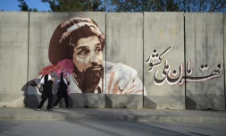 Des écoliÚres passent devant un mur recouvert d'un portrait du commandant Massoud, le 7 avril 2019 à Kaboul