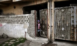 Une enfant regarde par une porte entrebâillée, le 2 mars 2017 à Mossoul pendant l'offensive entre les forces irakiennes et les jihadistes de l'EI