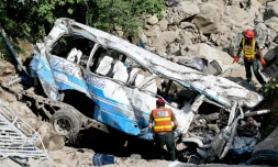 Des secouristes inspectent la carcasse d'un bus qui a plongé dans le ravin faisant 23 morts à proximité de la ville pakistanaise de Kahuta, près d'Islamabad, le 24 août 2024