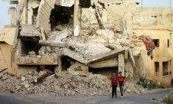 Deux jeunes Syriens marchent au milieu des ruines dans un secteur rebelle de la ville de Deraa, dans le sud de la Syrie, le 20 avril 2018