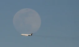 Un avion de la compagnie vénézuélienne Rutaca passe devant la lune, vu depuis l'aéroport international Simon Bolivar à Maiquetia, Venezuela, le 3 décembre 2025