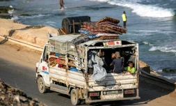 Des déplacés palestiniens fuyant le nord de la bande de Gza en direction du sud du terrtoire roulent à bord d'un camion chargé d'effets personnels sur la route côtière du camp de Nousseirat (centre), le 30 août 2025
