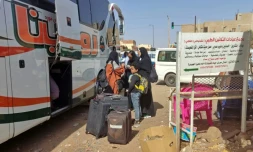 Des personnes attendent avec leurs bagages devant un bus à Khartoum pendant des combats entre l'armée et les paramilitaires, le 8 mai 2023 au Soudan