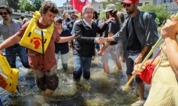 Le leader de la France insoumise (LFI) et chef de la coalition de gauche Nupes (Nouvelle allinace progressiste écologiste et sociale) Jean-Luc Melenchon (centre) serre la main de ses parisans alors qu'il traverse la rivière Clain près du pont de Joubert à Poitiers, sud-ouest de la France, le 2 juin 2022
