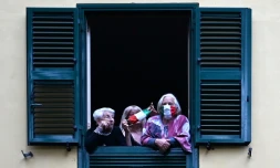 Des habitants à leur fenêtre pour écouter des musiciens qui se produisent dans la cour d'une immeuble d'habitations à loyer modéré dans la banlieue de Rome, le 18 avril 2020 