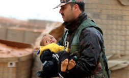 Un membre des forces armées jordaniennes transporte un enfant dans une zone tampon à la frontière entre la Syrie et la Jordanie, le 1er mars 2017
