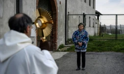 Le père Don Kresimir Busic prie avec une paroissienne à Manta, dans le Piedmont, dans le nord de l'Italie, dans le cadre d'une procession religieuse pour bénir les maisons contre le coronavirus, le 25 mars 2020