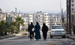 Des habitants marchent dans une rue de l'ancien quartier rebelle de Zebdiye, le 23 décembre 2016 à Alep, en Syrie