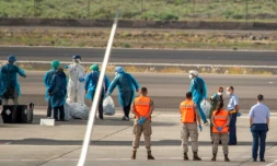 Des passagers espagnols en combinaison de protection, évacués du navire touché par un foyer d'hantavirus, attendent de monter à bord d'un avion à l'aéroport de Tenerife, le 10 mai 2026

