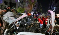 Des passants et des secouristes inspectent la carcasse du minibus dans lequel une bombe a explosé, à Jaramana, près de la capitale syrienne, Damas, le 6 août 2026