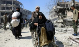 Une syrienne en fauteil roulant évacue la localité de Jisrine dans la Ghouta orientale, en direction de zones sous contrôle gouvernemental, le 17 mars 2018