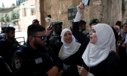 Une palestinienne manifeste et brandit un exemplaire du Coran devant un membre des forces de sécurité israéliennes, à Jérusalem, le 20 juillet 2017