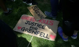 "La cupidité tue", clame cette pancarte sur le sol, lors d'une manifestation le 21 juin 2017 près de la Grenfell Tower de Londres, où au moins 80 personnes ont trouvé la mort dans le gigantesque incendie du 14 juin