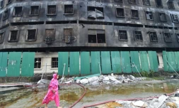 Une femme passe, le 10 juillet 2021, devant la carcasse de l'usine dont l'incendie a fait 52 morts, à Rupganj, dans la banlieue de Dacca