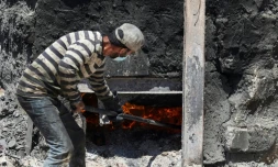 Un ouvrier palestinien allume une cuve contenant une tonne de plastique afin de distiller le pétrole qui le compose, à Jabalia, dans la bande de Gaza, le 23 août 2022