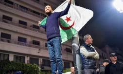 Un Algérien brandit le drapeau national lors de rassemblements dans les rues de la capitale Alger, le 11 mars 2019 au soir