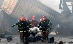 Des pompiers portent le corps d'une victime d'un incendie dans un entrepôt de conteneurs, le 5 juin 2022 à Sitakunda, au Bangladesh