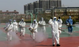 Des bénévoles désinfectent la cour d'une école avant sa réouverture, le 12 avril 2020 à Weifang, dans l'est de la Chine