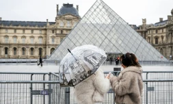 Des visiteuses devant le musée du Louvre et la pyramide conçue par l'architecte sino-américain Ieoh Ming Pei, le 12 janvier 2026 à Paris