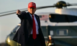 Le président américain Donald Trump fait signe de la main à une équipe de télévision au moment de monter à bord d'Air Force One, à la base Andrews près de Washington, le 28 février 2025