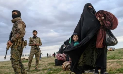 Une femme et son enfant passent devant des membres des Forces démocratiques syriennes, après avoir fui le dernier réduit du groupe Etat islamique à Baghouz, en Syrie, le 28 février 2019 