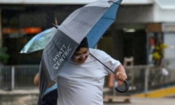 Un homme s'abrite de la pluie et du vent apportés par le typhon Saola à Hong Kong vendredi 1er septembre 2023