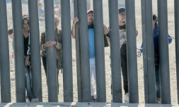 Des candidats à l'immigration aux Etats-Unis, venus du Honduras, regardent à travers le mur frontalier à San Ysidro (Californie)