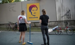 Les artistes de rue Eleanor et Juliette du collectif  "Merci Simone" devant un poster du portrait de Simone Veil qu'elles viennent de poser à Paris, le 28 juin 25018