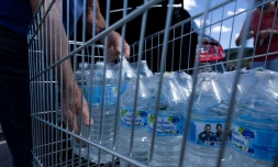 Un homme met des bouteilles d'eau dans sa voiture sur le parking d'un supermarché à Gérardmer dans l'est de la France, le 3 août 2022